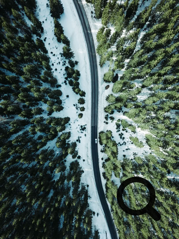 Beeindruckende Vogelperspektive einer schneebedeckten Stra&szlig;e, die sich durch einen dichten Nadelwald schl&auml;ngelt. Die klaren Kontraste zwischen Schnee und Gr&uuml;n schaffen eine faszinierende Winterlandschaft.